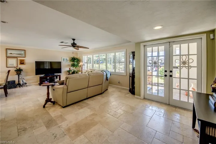 Living area with french doors, stone tile floors, ceiling fan, ornamental molding, and recessed lighting