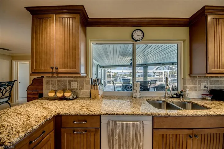 Kitchen featuring crown molding, light stone counters, decorative backsplash, wood finish cabinets, and dishwashing machine