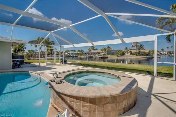 Outdoor pool with a sunroom, a patio area, a residential view, an in-ground hot tub, and glass enclosure