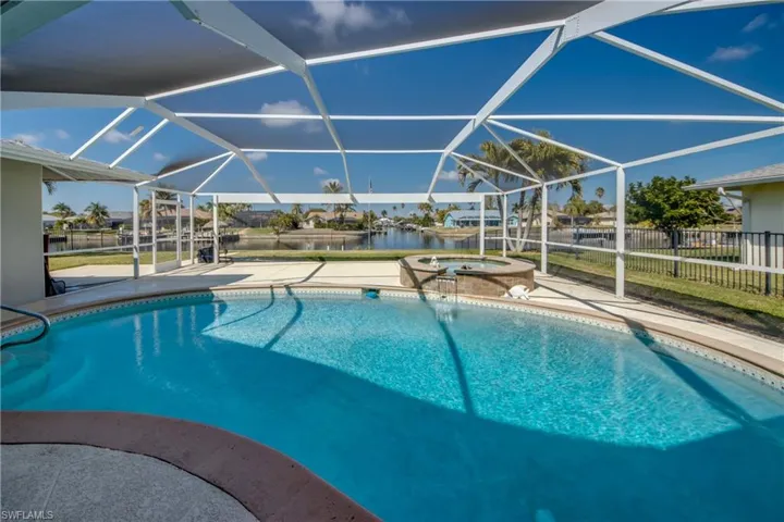 Integrated pool / spa with a sunroom, a patio, glass enclosure, and a residential view