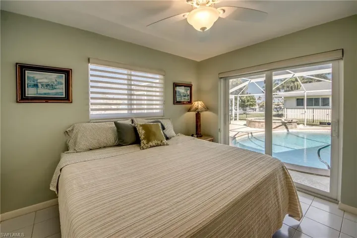 Tiled bedroom with a sunroom, a ceiling fan, and access to exterior