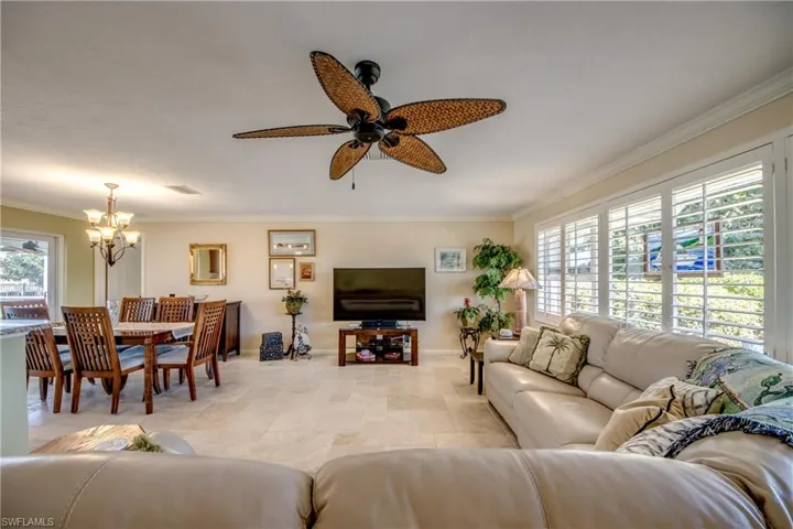 Living area with healthy amount of natural light, suspended lighting, ceiling fan, and crown molding