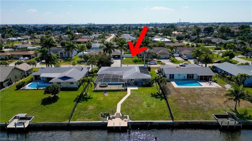 Aerial view of residential area featuring a pool and a large body of water