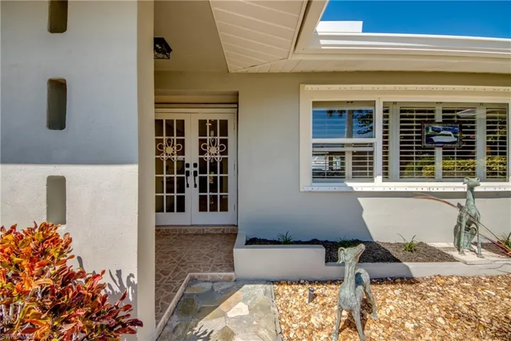 View of exterior entry with french doors, stucco siding, and covered porch