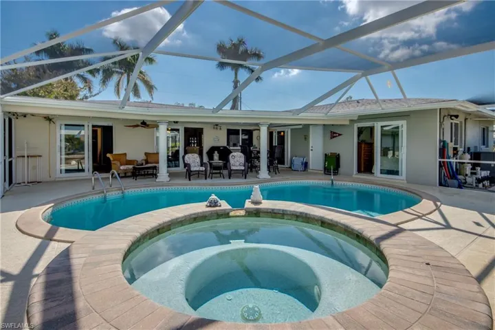 Integrated pool / hot tub featuring a patio, a sunroom, glass enclosure, and outdoor furniture