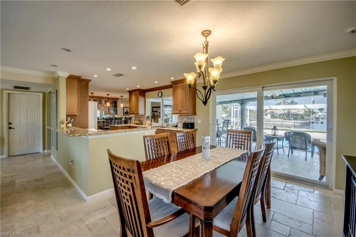 Dining room featuring stone tile floors, crown molding, and a chandelier