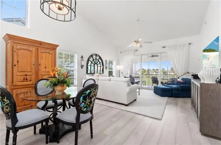 Dining room with light wood finished floors, high vaulted ceiling, and ceiling fan