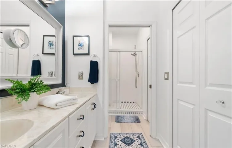 Bathroom with a stall shower, double vanity, wood finished floors, and a sink