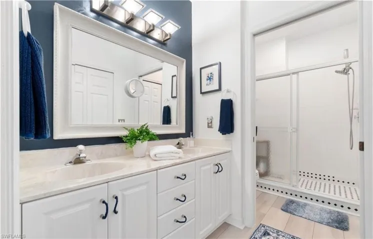 Bathroom with double vanity, a sink, toilet, and a shower stall