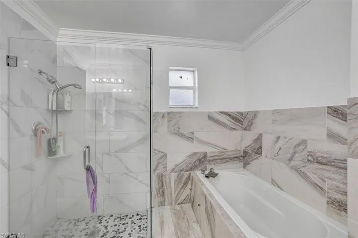 Full bath with a bath, a stall shower, and ornamental molding