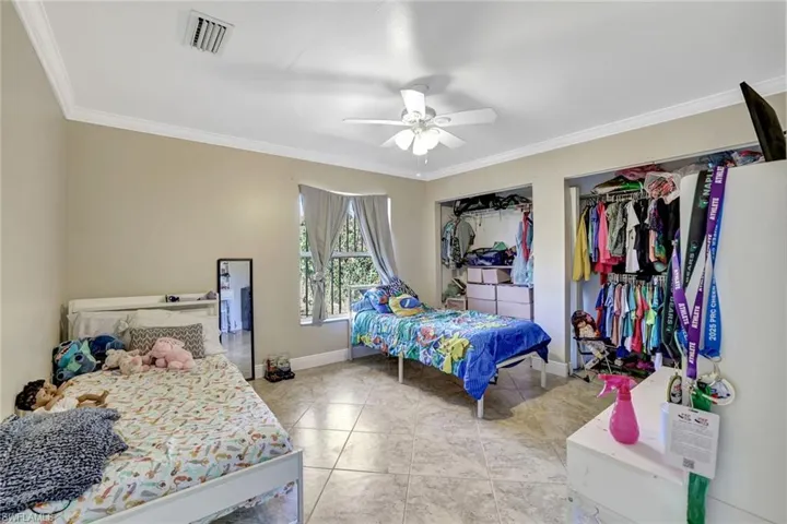 Bedroom featuring ornamental molding, ceiling fan, and multiple closets