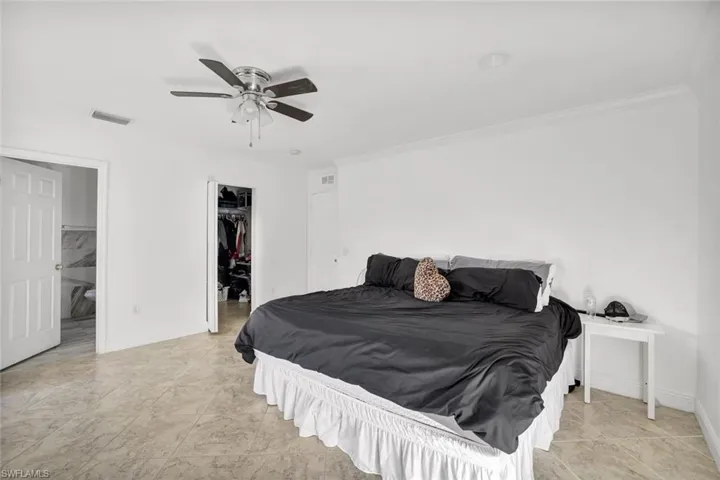 Bedroom featuring a walk in closet, a ceiling fan, crown molding, and connected bathroom