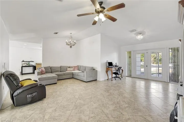 Living room featuring an office area, vaulted ceiling, a chandelier, and a ceiling fan