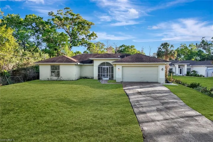 Ranch-style home featuring stucco siding, a front yard, asphalt driveway, and a garage