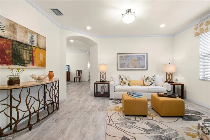 Living area /den, office, arched walkways, light wood-type flooring, ornamental molding, and recessed lighting