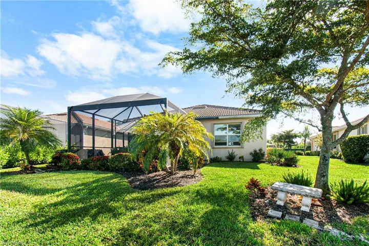Back of house with a lanai, a sunroom, a yard, and stucco siding