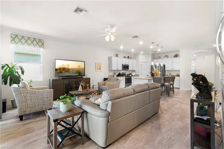 Living room with arched walkways, crown molding, and a ceiling fan
