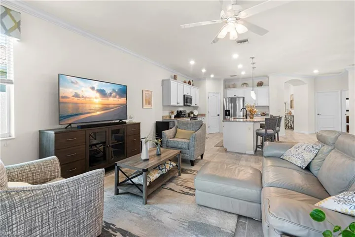 Living room featuring ornamental molding, arched walkways, a ceiling fan, and recessed lighting