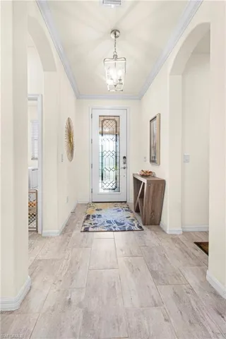 Foyer featuring arched walkways, a chandelier, and ornamental molding