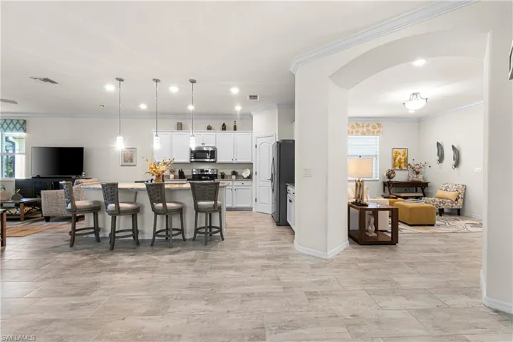 Kitchen featuring open floor plan, arched walkways, a breakfast bar area, an island with sink, and decorative light fixtures