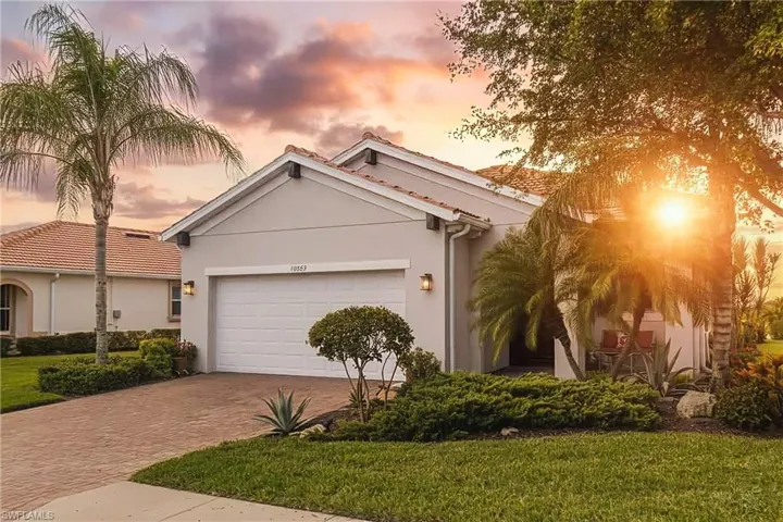 View of front of house featuring stucco siding, a yard, decorative driveway, and a garage