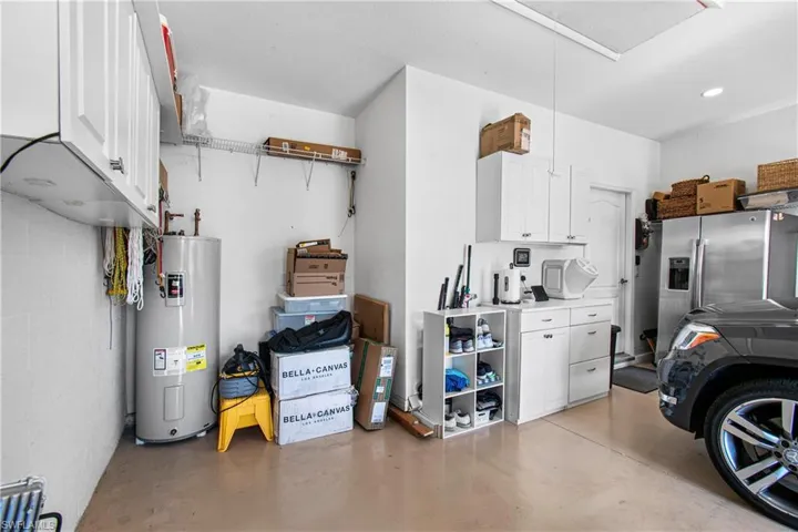 Garage featuring stainless steel refrigerator with ice dispenser and electric water heater, extra 4' deep garage for golf cart parking