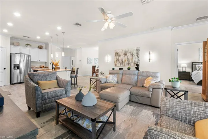Living area with crown molding, recessed lighting, ceiling fan, and light wood-style flooring