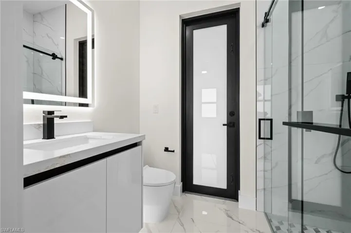 Full bathroom with marble finish floor, toilet, vanity, and a marble finish shower