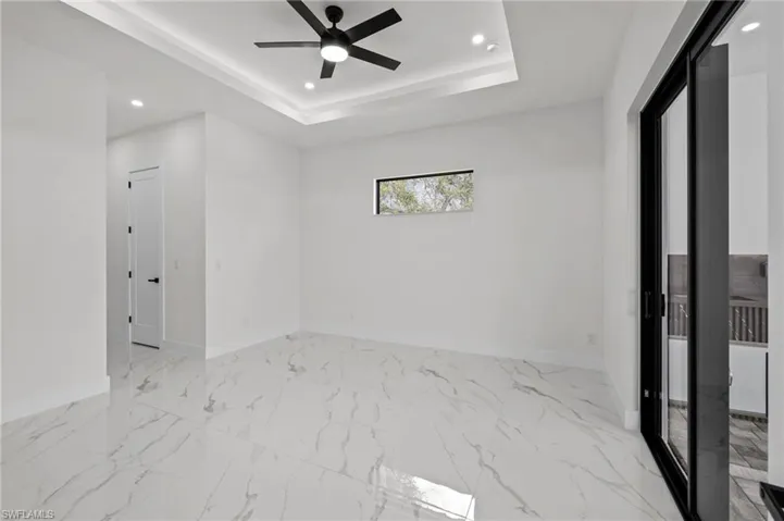 Spare room with recessed lighting, a ceiling fan, baseboards, marble finish floor, and a raised ceiling
