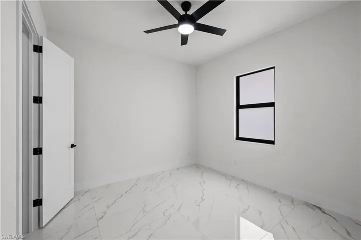 Spare room featuring marble finish floor, a ceiling fan, and baseboards