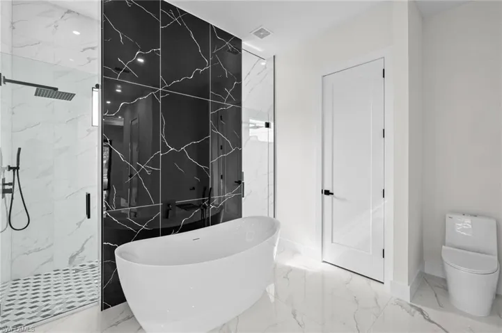 Full bathroom with marble finish floor, a marble finish shower, visible vents, and a freestanding tub