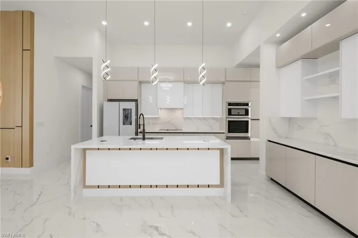 Kitchen featuring marble finish floor, modern cabinets, a sink, and freestanding refrigerator