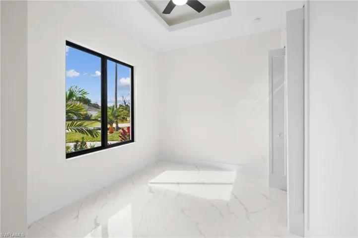 Unfurnished room with marble finish floor, baseboards, and a tray ceiling