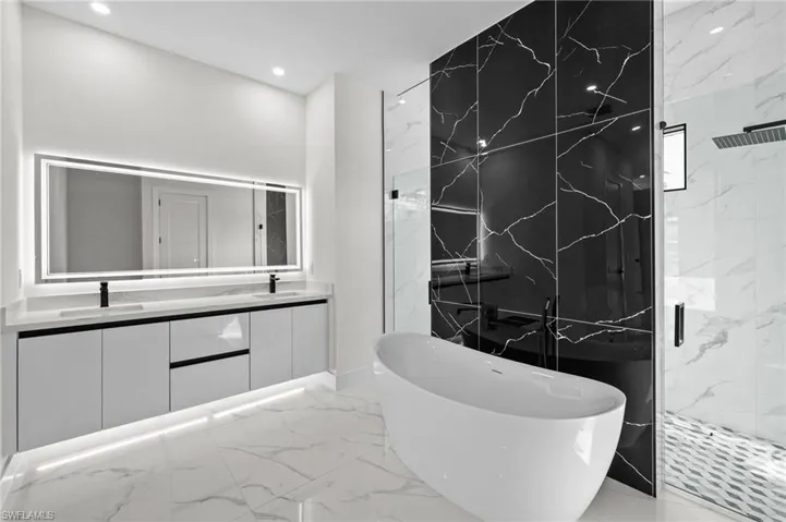 Bathroom with marble finish floor, stone wall, and a sink