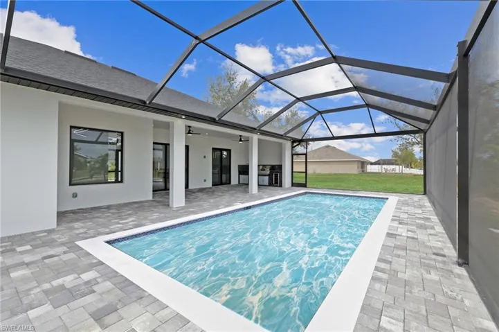 Pool featuring glass enclosure, a patio area, ceiling fan, and a lawn