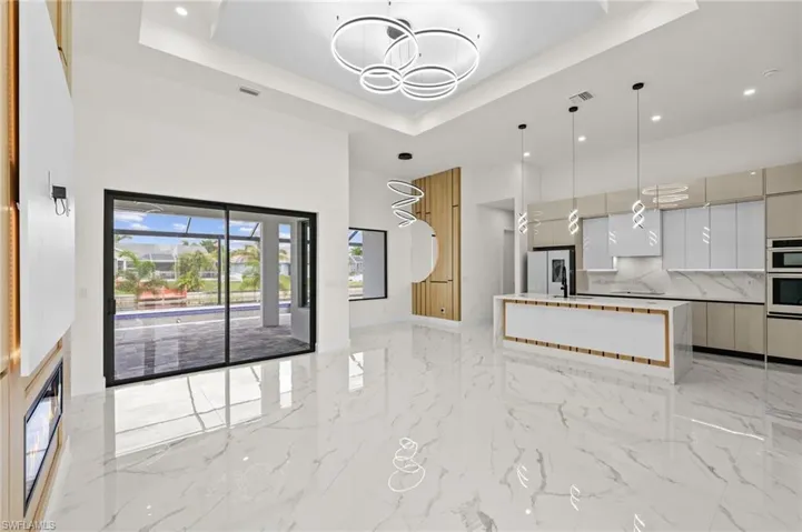 Kitchen featuring a towering ceiling, modern cabinets, marble finish floor, a tray ceiling, and fridge