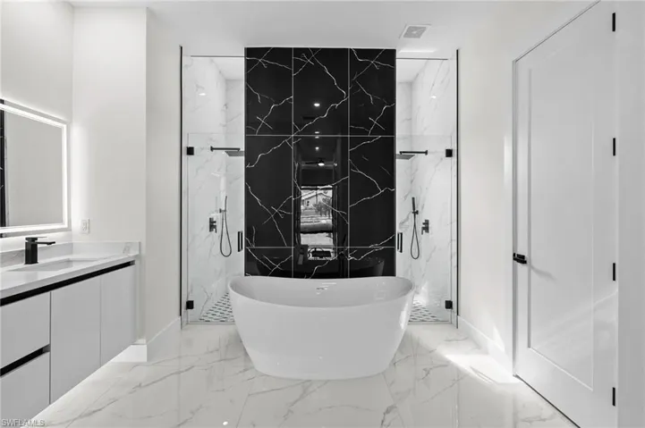 Bathroom with a freestanding tub, visible vents, vanity, marble finish floor, and a marble finish shower