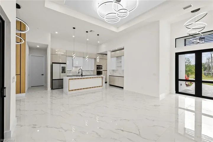Kitchen featuring freestanding refrigerator, marble finish floor, an inviting chandelier, and modern cabinets