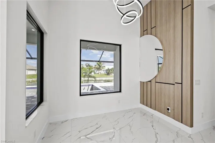 Empty room featuring marble finish floor, plenty of natural light, and baseboards