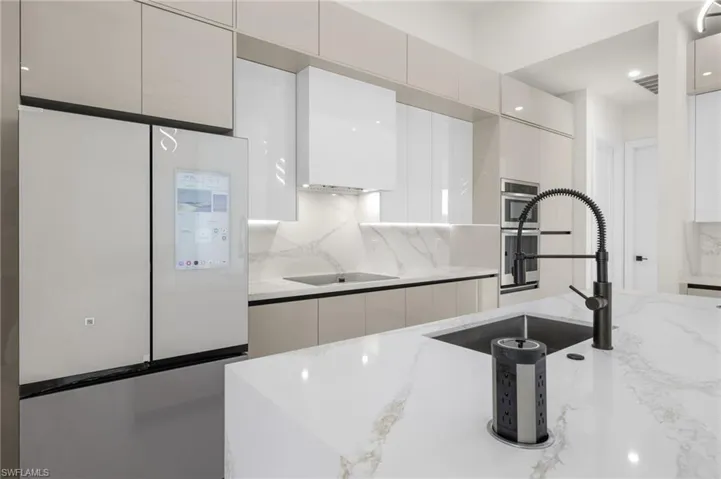 Kitchen with tasteful backsplash, freestanding refrigerator, white cabinetry, a sink, and modern cabinets