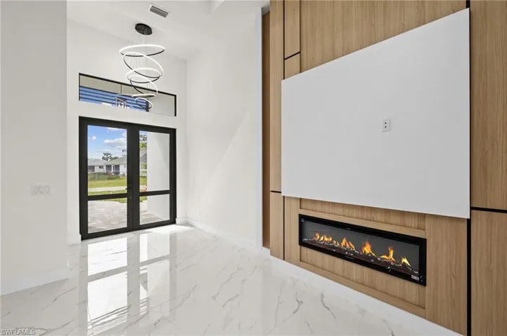Unfurnished living room featuring marble finish floor, baseboards, and french doors
