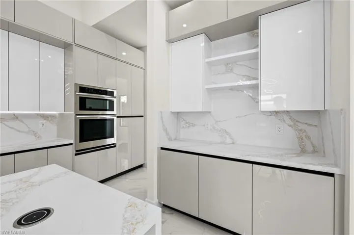 Kitchen featuring light stone counters, marble finish floor, tasteful backsplash, white cabinetry, and modern cabinets