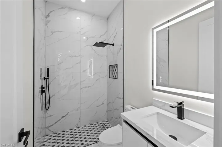 Bathroom featuring vanity, a marble finish shower, and toilet