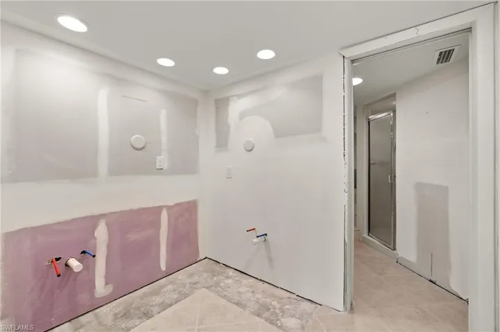 Bathroom with a shower with door and tile patterned floors