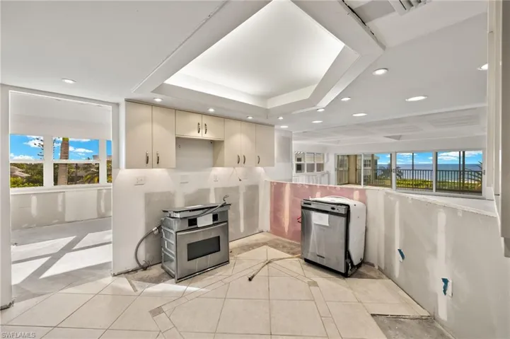 Kitchen with cream cabinets, light tile patterned floors, and a raised ceiling