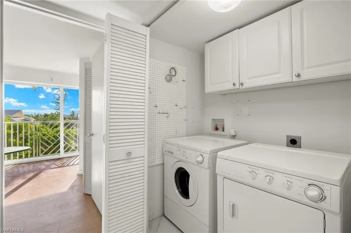 Clothes washing area with light hardwood / wood-style floors, washer and dryer, and cabinets