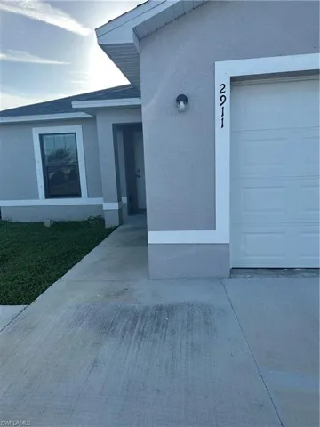 Doorway to property featuring stucco siding and a garage