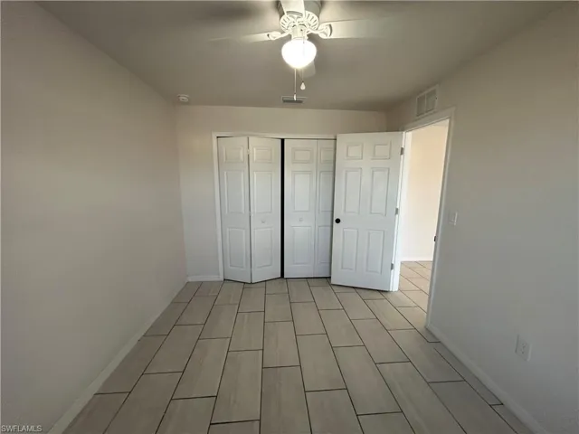 Unfurnished bedroom featuring wood finish floors, a closet, and a ceiling fan