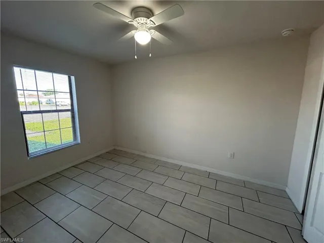 Empty room featuring light tile patterned floors and ceiling fan