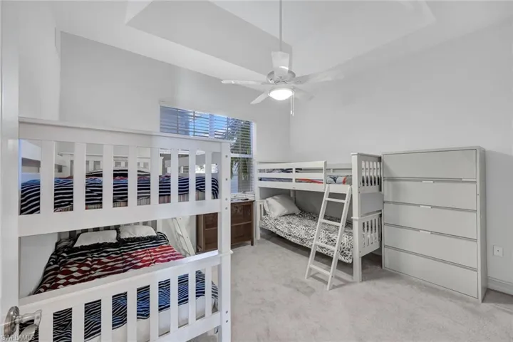 Bedroom featuring light carpet, a tray ceiling, and ceiling fan